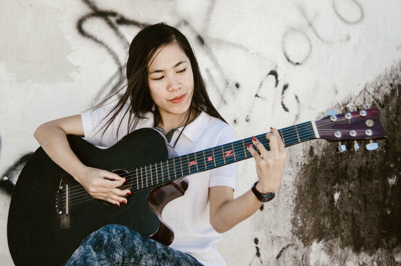 A woman "love yourself" by playing guitar. 