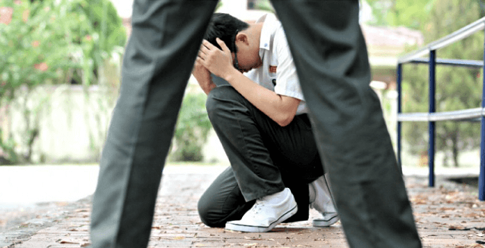 A student covering his face to avoid physical bullying. Let's prevent bullying in schools from today!