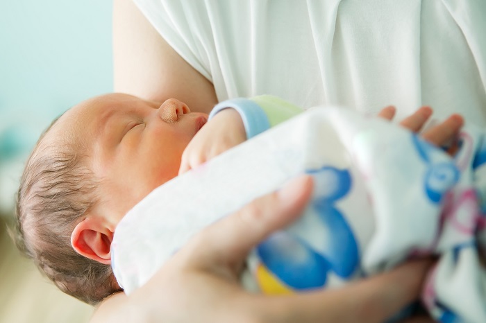 baby sleeping in mother's arm