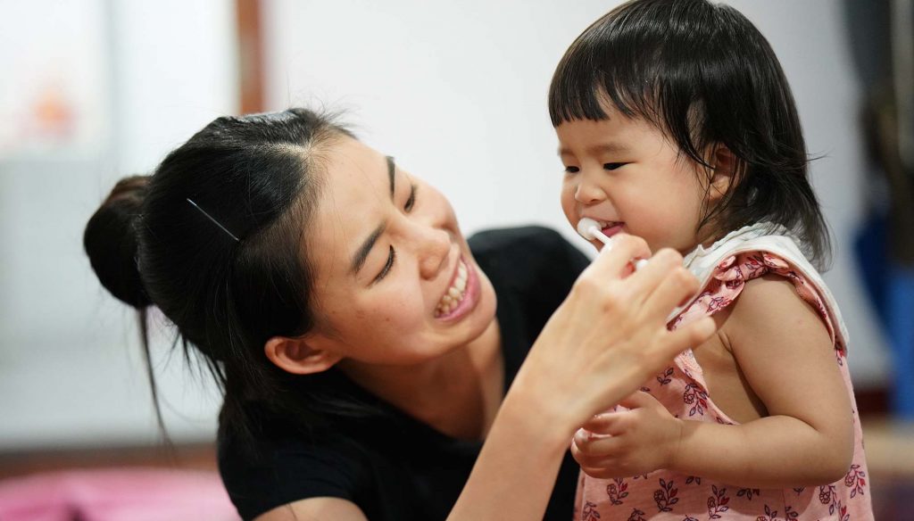 mother is brushing daughter's teeth 