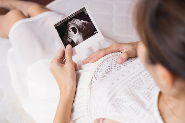 Pregnant Woman Looking At Scan Photo