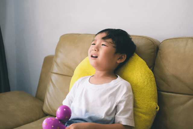 A little boy is throwing tantrum on the sofa.