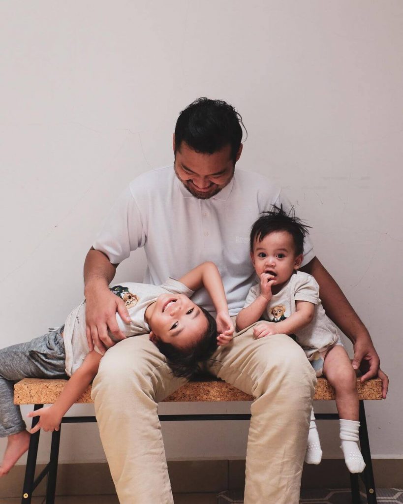 A father is looking happily at his two sons.