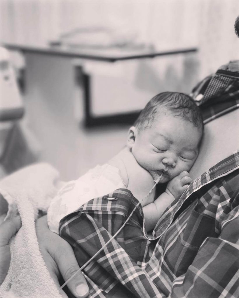 A newborn is laid on his parent's chest.