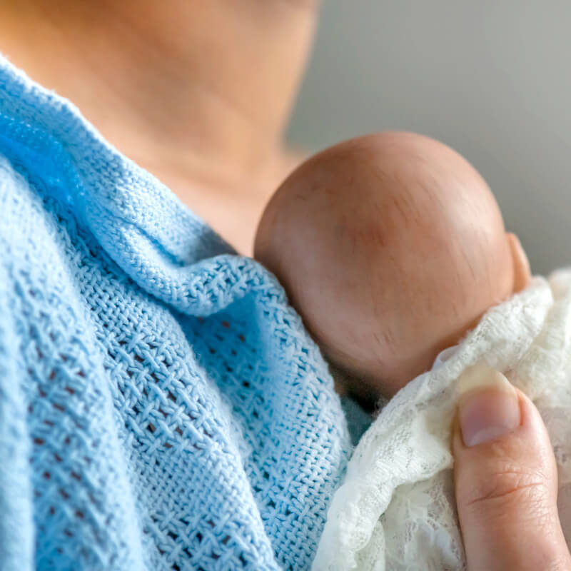 A mum holding her baby close to skin ready for breastfeeding