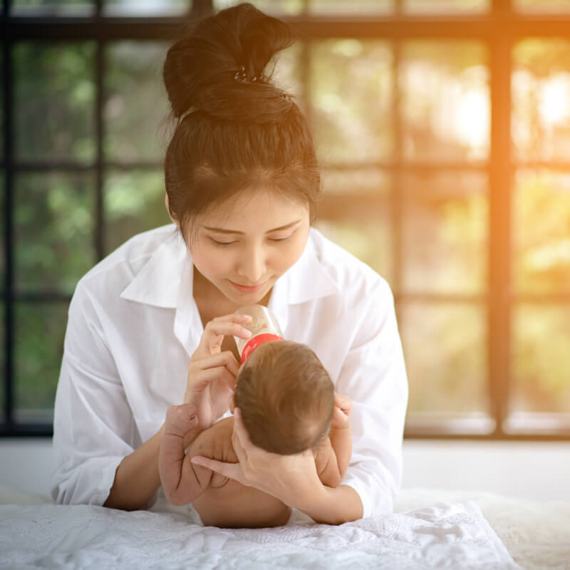 A mum feeding milk in a bottle