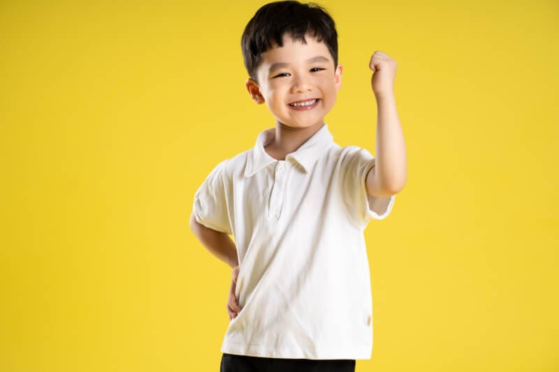 young boy on yellow background with white polo shirt