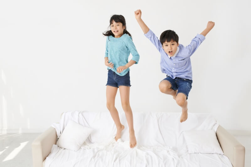 two children jumping on the bed