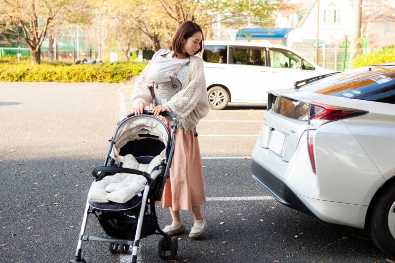 mother with baby carrier and stroller at carpark