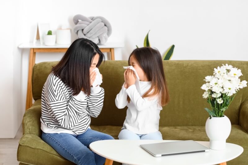 woman and daughter sneezing with tissue together